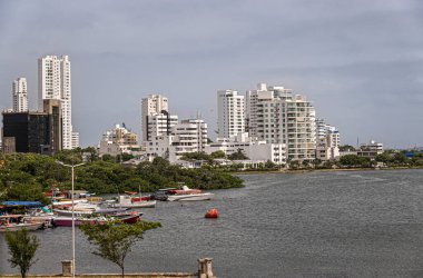 Cartagena, Kolombiya - 25 Temmuz 2023: Bocagrande yarımadasının kuzey kısmında küçük tekneleri ve yeşil yaprakları olan uzun beyaz binalar.