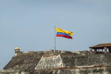 Cartagena, Kolombiya - 25 Temmuz 2023: Gri-bej taş San Felipe de Barajas Kalesi Mavi gökyüzüne karşı ulusal bayrak