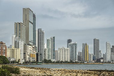 Cartagena, Kolombiya - 25 Temmuz 2023: Bocagrande Mahallesi. Hyatt Regency otel kuleleri, Karayip Denizi 'nin sınırındaki mavi-gri bulutların altındaki diğer uzun modern binaların üzerinde.