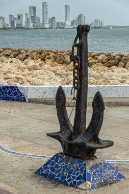 Cartagena, Colombia - July 25, 2023: Portrait, Avenida Santander, part of Bocagrande cityscape and anchor near Monumento Union de los Oceanos at rocky beach clipart