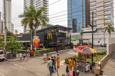 Cartagena, Kolombiya - 25 Temmuz 2023: Merkez Bocagrande Carrera 2. İnsanlar iş caddesinde yürüyor. McDonald 's fast food restoranı. Arkadaki yüksek binalar ve yeşil palmiye ağaçları.