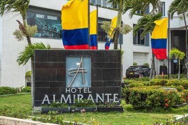 Cartagena, Kolombiya - 25 Temmuz 2023: Merkez Bocagrande Carrera 2. Otel Almirante girişi ve bahçedeki büyük tabela. Denizcilik bayrakları, kırmızı çiçekler, bitkiler ve ağaçlar.