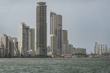 Cartagena, Colombia - July 25, 2023: Looking north over bay from Las Gaviotas pier over bay to tall historic ship at navy base. Cathedral dome visible. Tall buildings on north side Bocagrande clipart