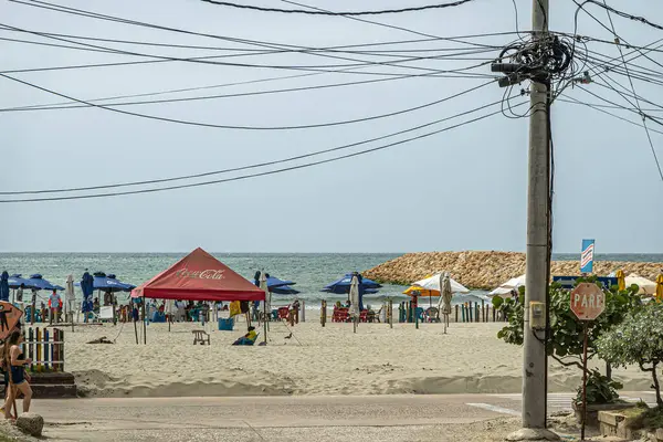 Cartagena, Kolombiya - 25 Temmuz 2023: Merkez Bocagrande Carrera 2, Carrera 1 ile sahilde buluştu. Coca-Cola çadırı ve diğer şemsiyeler. Açık mavi gökyüzünü kesen elektrik kabloları