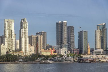 Miami, Florida, ABD - 29 Temmuz 2023: Biscayne Bulvarı boyunca Bayfront parkı ve dönme dolabın arkasında kıyı şeridi boyunca çok sayıda eğlence şirketi bulunan gökdelenler çizgisi