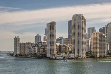 Miami, Florida, ABD - 29 Temmuz 2023: günbatımında Brickell Key Adası 'ndaki yüksek binalar. Sahildeki Tequesta noktaları arasındaki Centinel heykeli. Biraz yeşil yaprak. Yatlar suyun üstünde.