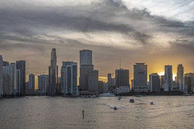 Miami, Florida, ABD - 29 Temmuz 2023: River mouth 'tan ana kara N, kıtalararası oteli olan günbatımı 19: 47 Skyline. Küçük motorlu yatlar koyu bulutlu suların altında