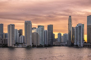 Miami, Florida, ABD - 29 Temmuz 2023 Brickell Key Adası 'ndaki binaların üzerinde gün batımı kırmızı gökyüzü 19: 47' de nehir ağzı boyunca. Tequesta noktaları arasındaki Centinel heykeli