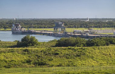 Port Canaveral, Florida, ABD - 30 Temmuz 2023: HDS Maverick gemisiyle mavi su üzerinde mavi gökyüzünün altına kenetlenmiş yeşil manzara