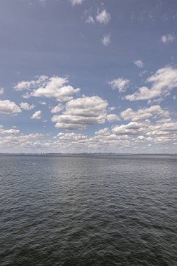 New York, New York, ABD - 1 Ağustos 2023: Mavi bulutlar altında okyanus yaklaşımından City Skyline 'a uzun bir portre.  
