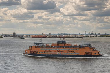 New York, New York, ABD - 1 Ağustos 2023: Yakın plan, New Jersey limanı ve Bayonne enerji merkezi olan Orange Staten Island feribot, mavi bulutların altında