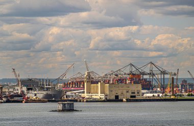 New York, New York, ABD - 1 Ağustos 2023: Bayonne limanının arkasındaki konteyner terminali ve New Jersey limanındaki tamir merkezi mavi bulutların altında. Konteyner kutuları ve kenetlenmiş gemiler.