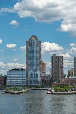 New York, New York, ABD - 1 Ağustos 2023: 25 ve 26 numaralı yeşil rıhtım arasında cam cepheli şehir merkezi binası. Hudson River 'dan doğruca N. Moore Sokağı' na bakıyorum. mavi bulut