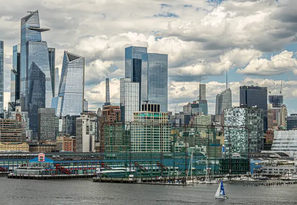 stock image New York, NY, USA - August 1, 2023: High net around Pier Chelsey golf operation and boat rental backed by pier 60. Skyscraper collection in back and lower fancy facades along Hudson river shoreline under blue cloudscape