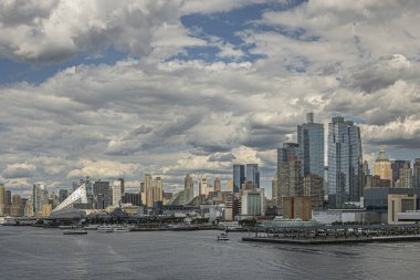 New York, New York, ABD - 1 Ağustos 2023: Hudson nehir kıyıları Javits Center 'dan rıhtım 76' ya ve mavi bulutlar altında üçgen bina. 67. rıhtımda gemi müzesi taşıyan korkusuz uçak.