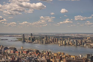 New York, New York, ABD - 2 Ağustos 2023: Panorama, Jersey City sahil şeridi Esses 1 'den kuzey Hudson nehrinin yukarısına Hollanda Tüneli rıhtımını geçince Empire State Binası' ndan görüldüğü gibi mavi bulutların altında