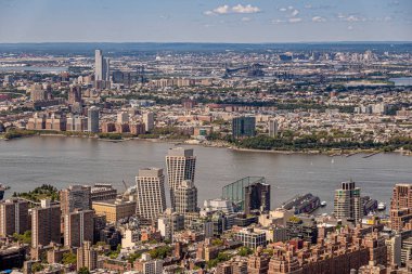 New York, New York, ABD - 2 Ağustos 2023: Her iki şehir ormanı da Hudson nehrinin Jetsey City Kalesi nokta parkında ve ötesinde Empire State Binası 'ndan mavi gökyüzünün altında geniş panorama.