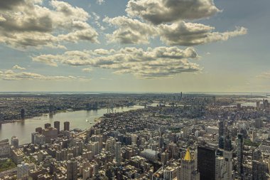 New York, New York, ABD - 2 Ağustos 2023: Manhattan aşağı doğu yakası ormanı Manhattan Köprüsü ve Doğu nehrine çıkıyor, Empire State Binası 'ndan mavi bulutların altında görülüyor. New York Yaşam Binası Altın Zirve