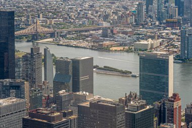 New York, New York, ABD - 2 Ağustos 2023: Franklin D Roosevelt East River 'daki dört özgürlük parkı Ed Koch Queensboro Köprüsü altında Manhattan yüksek binaları arasında Empire State Binası' ndan görüldü. Çevrede şehir ormanı