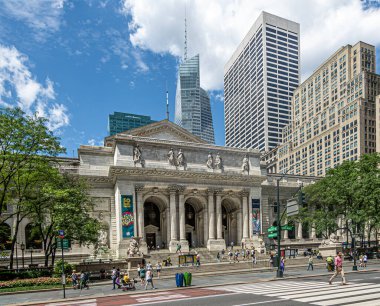 New York, New York, ABD - 2 Ağustos 2023: 5. Cadde 'deki New York Halk Kütüphanesi Binası ve mavi bulutlar altında yayalar. Arkada bir Vanderbilt gökdeleni var. Yeşil yaprak