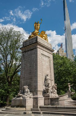 New York, New York, ABD - 2 Ağustos 2023: Maine, SW köşesindeki Central Park 'ın mavi bulutların altındaki heykel heykeli. Gökdelenler ve yeşil yapraklar