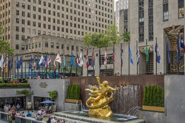 New York, New York, ABD - 3 Ağustos 2023: Rockefeller Center 'daki Prometheus heykeli ve çeşmesi. Bayraklar ve etraftaki insanlar