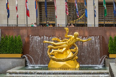 New York, New York, ABD - 3 Ağustos 2023: Frontal yakın çekim. Prometheus heykeli ve fıskiyesi Rockefeller merkezinde. Bayraklar ve içeri bakan insanlar