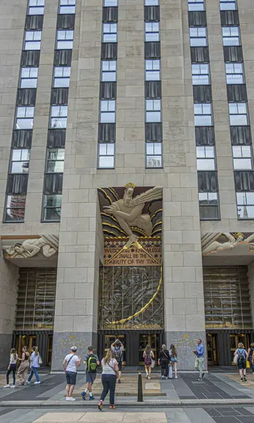 stock image New York, NY, USA - August 3, 2023: Main entrance to Comcast building at Rockefeller Plaza. Pedestrians and Classical themed murals, sound, wisdom and light above doors