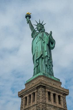 New York, New York, ABD - 4 Ağustos 2023: Sağdan Özgürlük Güzeli heykeli, mavi bulutlara karşı