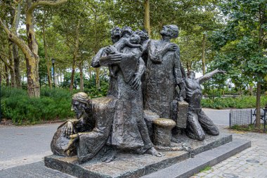 New York, New York, ABD - 4 Ağustos 2023: Battery Park 'ta Luis Sanguino' nun göçmen anıtı. Arkadaki yeşil yapraklar.