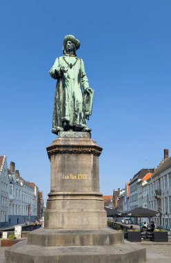 Brugge, Flanders, Belçika - 25 Haziran 2024: Ressam Jan Van Eyck heykeli, ön manzara mavi gökyüzüne karşı yeşil bronz.