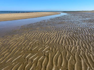 Knokke-Soygunu, Flanders, Belçika - 24 Haziran 2024: Islak kum dalgaları ve Kuzey Denizi Sahili 'nde gözün mavi gökyüzünün altında görebildiği kadar uzun marina