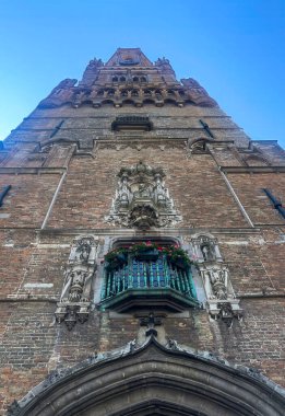 Brugge, Flanders, Belçika - 25 Haziran 2024: Mavi gökyüzüne karşı Halletoren ön cephesi boyunca balık gözü