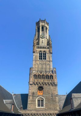 Brugge, Flanders, Belçika - 25 Haziran 2024: Belfry, Halletoren mavi gökyüzüne karşı iç avludan görüldü