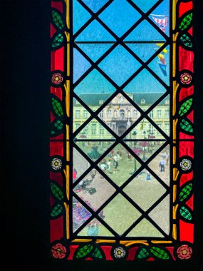 Brugge, Flanders, Belgium - June 25, 2024: Burg square with city government building seen through colorfully framed window on entryway to Basilica of the Holy Blood clipart