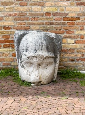 Portogruaor, Venice, Italy - June 26, 2024: Beige brick front facade of city hall or here, Community House on West side of Plazza della Republica. Focus on white stone statue against facade picturing a face clipart