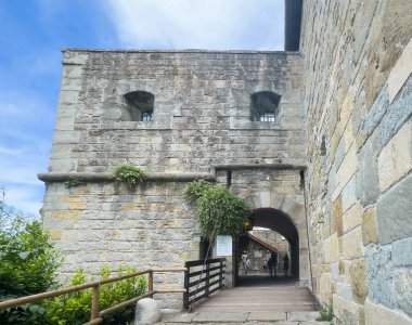 Trieste, İtalya - 27 Haziran 2024: Tarihi San Giusto Kalesi. Ana geçit ve kale kapısı, uzun taş duvarlar ve yeşil bitki örtüsü.