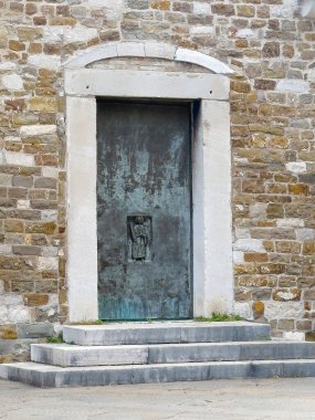 Trieste, İtalya - 27 Haziran 2024: Cattedrale di San Giusto Martire, San Giusto Kalesi Katedrali. Heykel, ana girişin sağ tarafındaki kapalı metal kapıda.