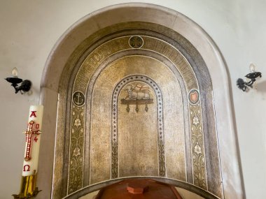 Trieste, İtalya - 27 Haziran 2024: Chiesa S. Antonio Vecchio, Yaşlı Anthony Kilisesi. Yukarıdaki duvar boyası, sırtında masumiyetin sembolü olan kutsal kuzu... 3 sembol: haç inançtır, çapa umuttur, ocak aşktır.