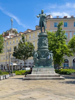 Trieste, İtalya - 27 Haziran 2024: Habsburg Piazza Venezia 'daki Maximilian heykeli. Boyalı cepheler ve arkada yeşil yapraklar.