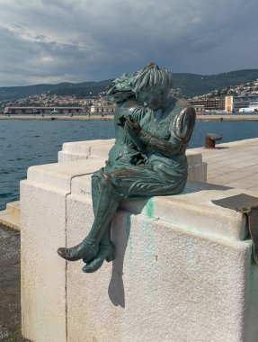 Trieste, İtalya - 27 Haziran 2024: Le Ragazze di Trieste heykeli Scale Reale 'de iki kız çocuğu, Adriyatik Denizi' ne girdi. Ufukta evleri olan ormanlık bir tepe. 2. Dünya Savaşı 'ndan sonra Tirestine kızlarının göçünü kutluyoruz.