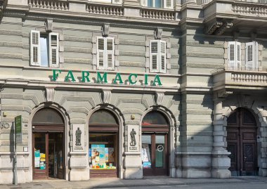 Trieste, İtalya - 29 Haziran 2024: De Lettenburg Eczanesi Piazza Giovanni 'deki tarihi binanın ön cephesi. Tanıtım posterleri ve 2 fresk heykeli olan pencereleri göster 
