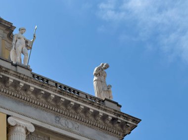 Trieste, İtalya - 29 Haziran 2024: Assicurazioni Generali tarihi binasının üst köşesi 2 Via Cesare Battisti. Mavi bulutların altındaki heykeller üstte.