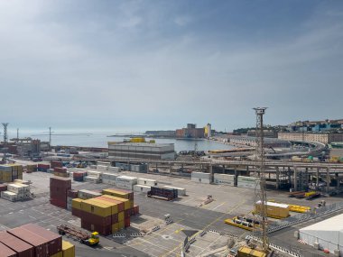 Trieste, İtalya - 29 Haziran 2024: Ticari liman. Kutuların ve operasyon yönetim binalarının olduğu konteynır terminali. Mavi bulutlar altındaki diğer rıhtımlar boyunca ambarlar ve ambarlarla birlikte limana giden otoyol