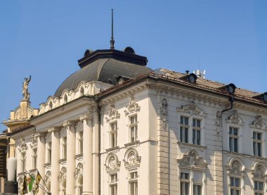 Ljubljana, Slovenia - June 28, 2024: The National Institute of Public Health (NIJZ) building facade top with statue of Neptune on next building, the Galerija Emporium under blue sky clipart