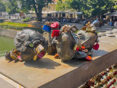 Ljubljana, Slovenya - 28 Haziran 2024: Kasap köprüsündeki balık ya da Ribe heykeli, asma kilitlerle dolu, ayrıca köprü kenarı