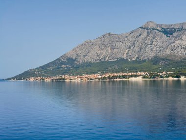 Orebiç, Hırvatistan - 30 Haziran 2024: Adriyatik 'ten bakıldığında: Turistik kent, uzun kumlu plajları ve uzun kayalık dağ sıraları ile kırmızı çatılı binalar
