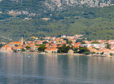 Orebiç, Hırvatistan - 30 Haziran 2024: Mary Kilisesi, Adriyatik Denizi kıyı şeridindeki Hristiyan kulelerine, otellere ve restoranlara yardım etti. Ormanlı dağ kanadı arkada.