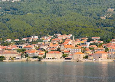 Orebiç, Hırvatistan - 30 Haziran 2024: Mary Kilisesi, Adriyatik Denizi kıyı şeridindeki Hristiyan kulelerine, otellere ve restoranlara yardım etti. Ormanlı dağ kanadı arkada.