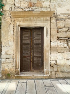 Korcula, Hırvatistan - 30 Haziran 2024: Eski ahşap kapı, heykel çerçeveli, eski taş duvar